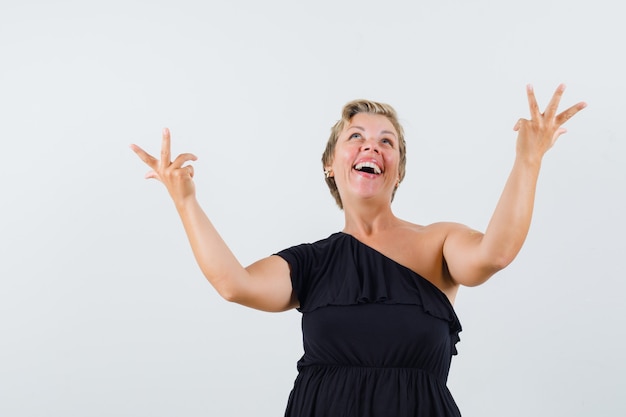 Glamorous woman in black blouse expressing her feeling with hands up and looking joyous 