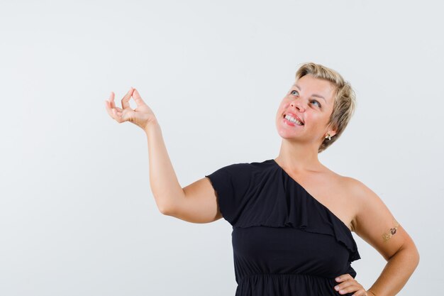 Free photo glamorous woman in black blouse posing like pulling something down and looking positive