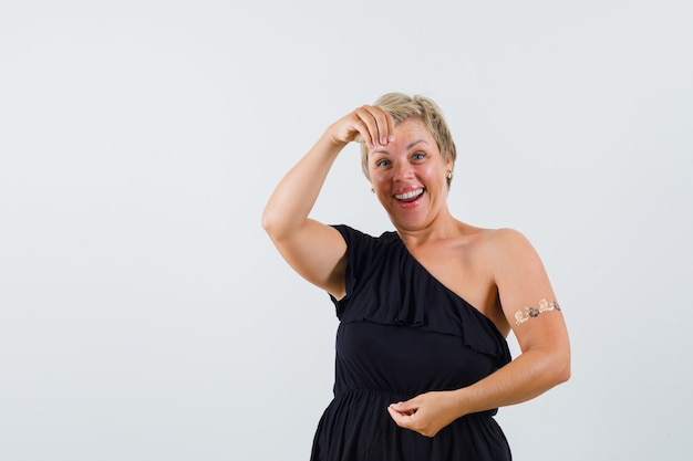 Glamorous woman in black blouse posing like showing something and looking cheery 