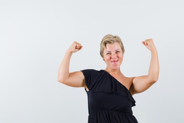 Glamorous woman in black blouse showing winner gesture and looking energetic 