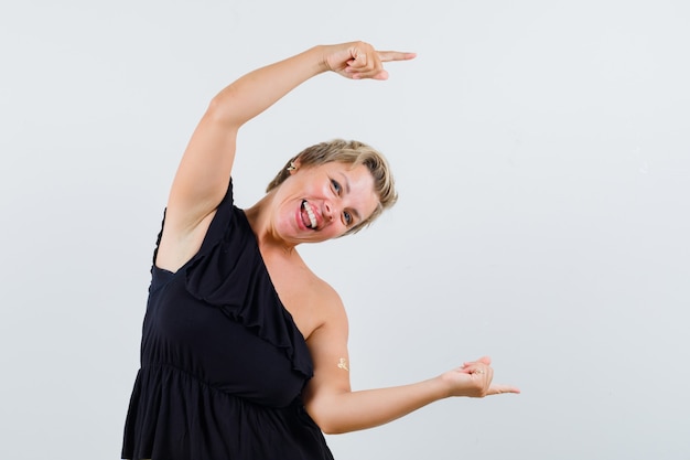 Free photo glamorous woman pointing aside over head in black blouse