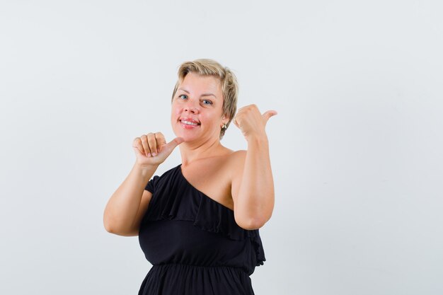 Glamorous woman pointing back in black blouse front view.