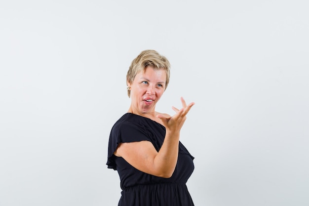 Free photo glamorous woman raising hand with questioning manner in black blouse and looking inquisitive