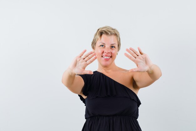 Glamorous woman showing her open palms in black blouse and looking confident 