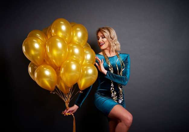 Donna affascinante con palloncini dorati sul nero