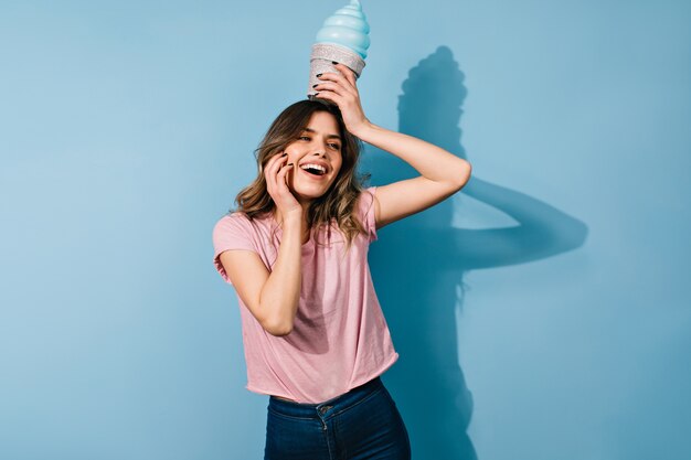 Glamorous young woman fooling around on blue wall