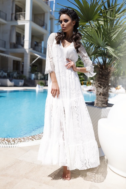 Foto gratuita glamours woman in the white light dress, summer, hot, brades, standing near the palm trees, sexy lady, beach, sand, sea, pool, waving dress,
