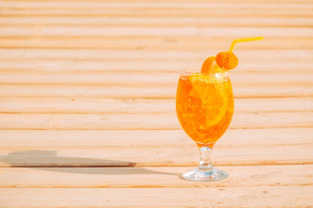 Glass of appetizing orange drink on wooden surface