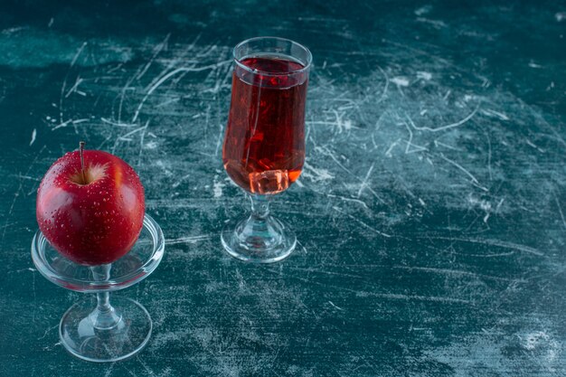 台座の上、大理石のテーブルの上にリンゴジュースとリンゴのグラス。