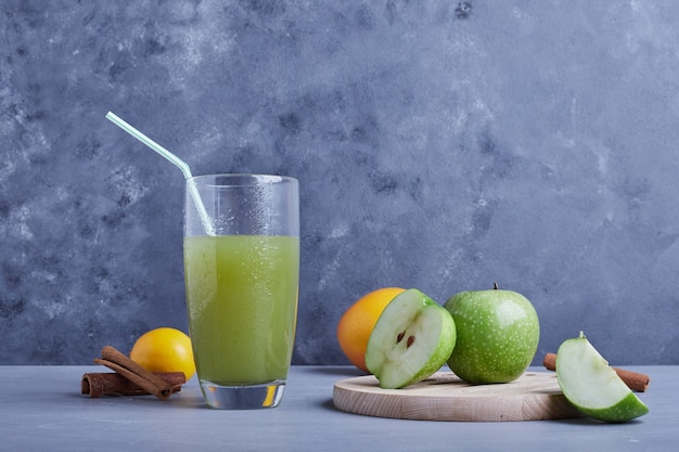 A glass of apple juice with cinnamon and fruit.