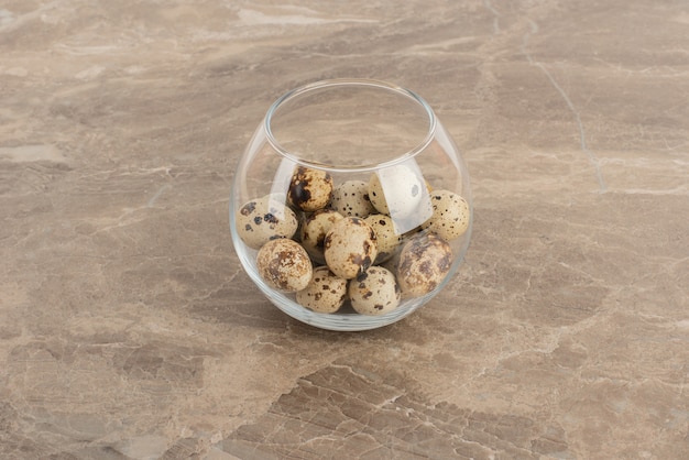 Glass ball of quail egg on marble background .