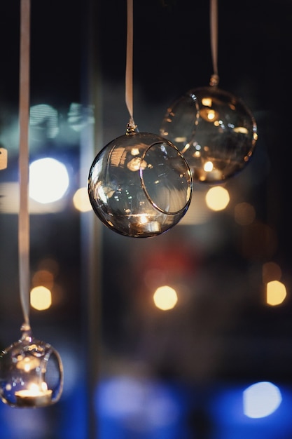 Glass balls with candles hang before the window