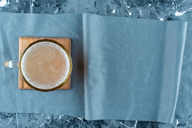 Free photo a glass of beer on a board on a pieces of fabric , on the blue table.