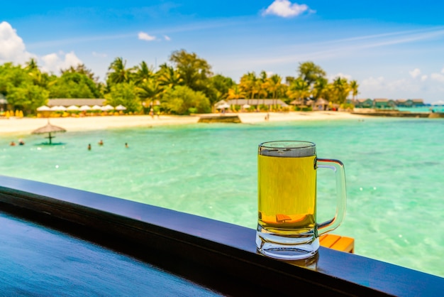A glass of beer with Beautiful tropical Maldives island .