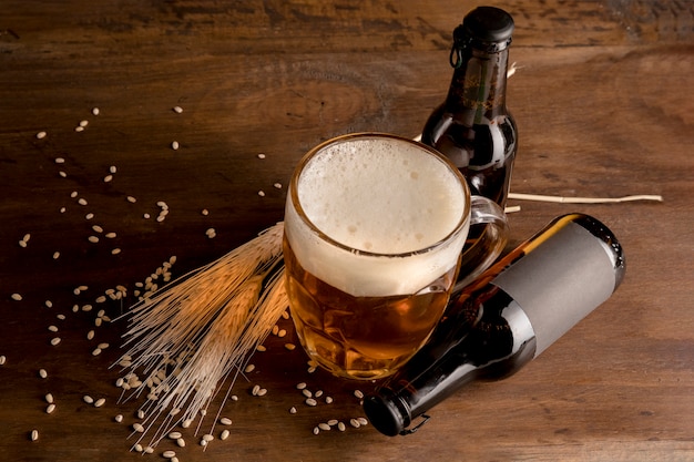 Foto gratuita bicchiere di birra con bottiglie marroni di birra sul tavolo di legno