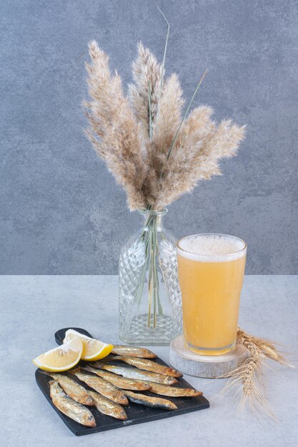 A glass of beer with fish and sliced lemon 