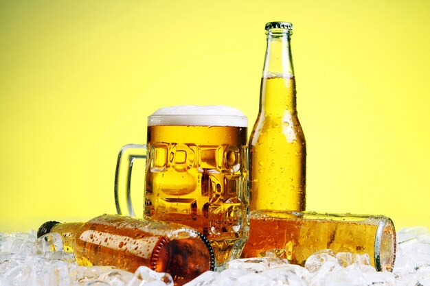 Glass of beer with foam on yellow background