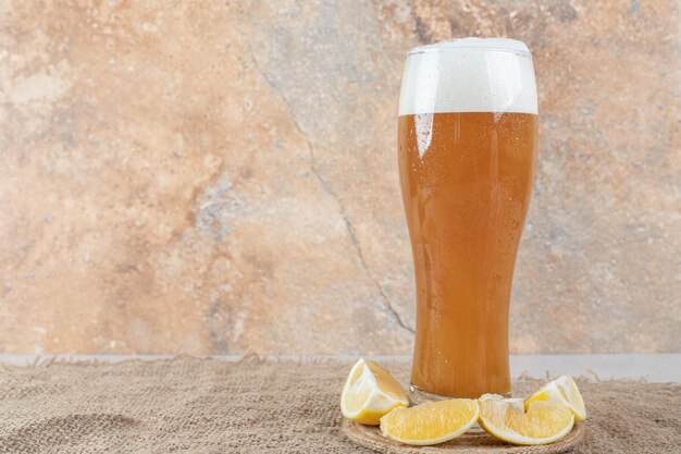 Glass of beer with lemon slices on burlap. 