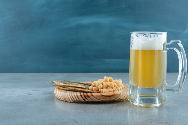생선과 완두콩의 나무 접시와 맥주 한 잔. 고품질 사진