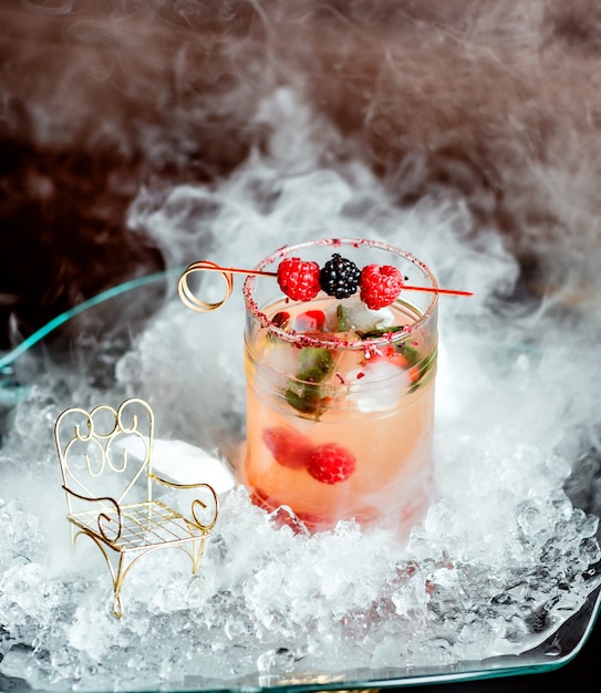 glass of berry cocktail garnished with raspberry and blackberry on skewers