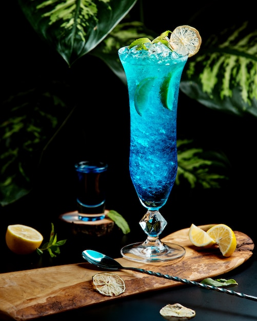 glass of blue lagoon garnished with lime slices