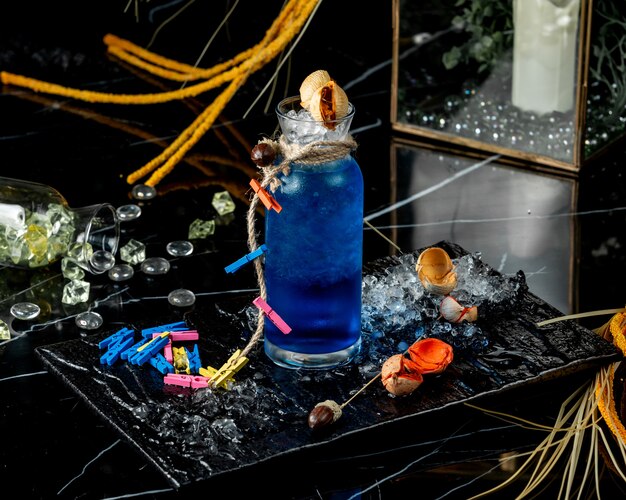 Free photo glass bottle of blue lagoon decorated with rope and colourful clothespin