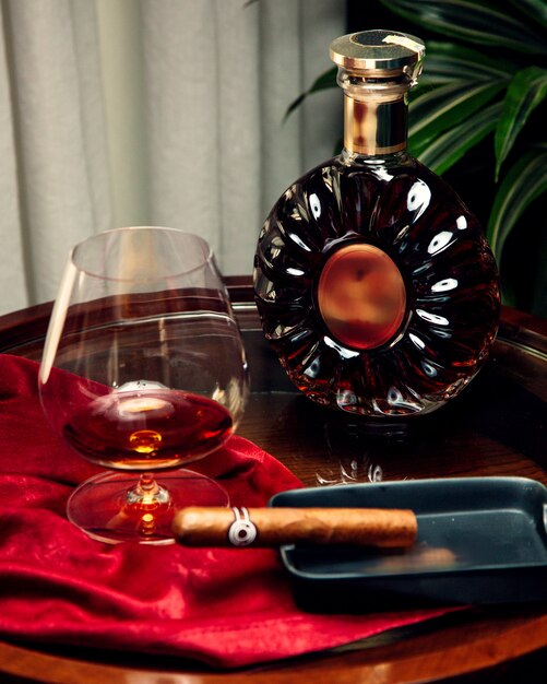 A glass and bottle of cognac and sigar