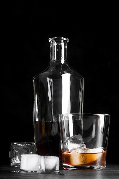Стакан и бутылка с коктейлем со льдом