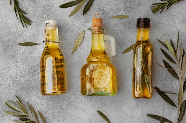 Стеклянная бутылка с оливковым маслом на сером фоне