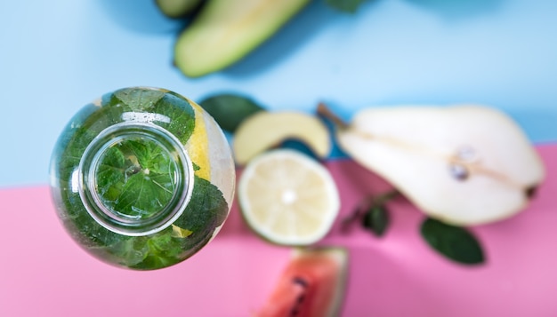 Glass bottles with natural drinks on a colored background