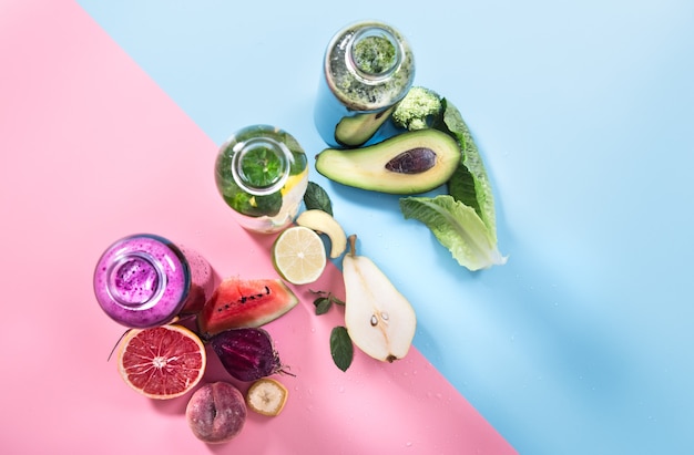 Free photo glass bottles with natural drinks on a colored wall