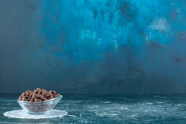 A glass bowl of corn rings on caster , on the blue background. High quality photo