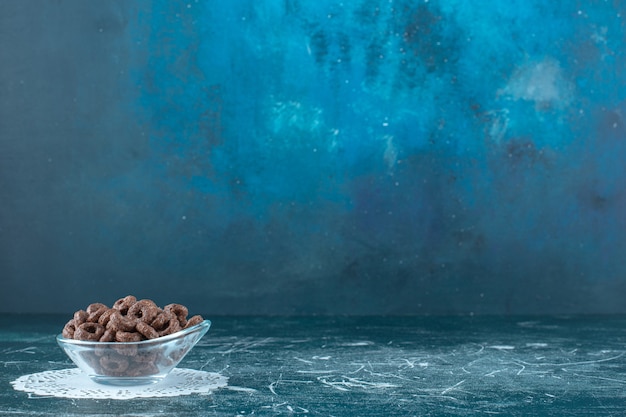 A glass bowl of corn rings on caster , on the blue background. High quality photo