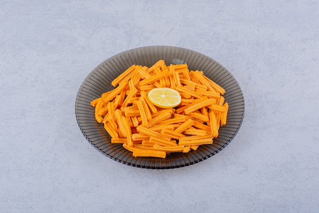 Glass bowl of crunchy potato chips on stone.