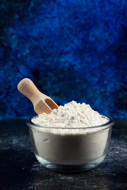 Glass bowl of flour on blue.