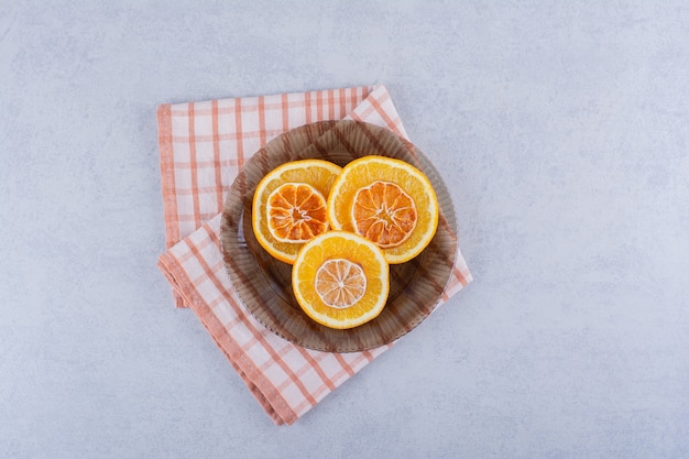 Glass bowl of fresh and dry orange slices on stone table. 