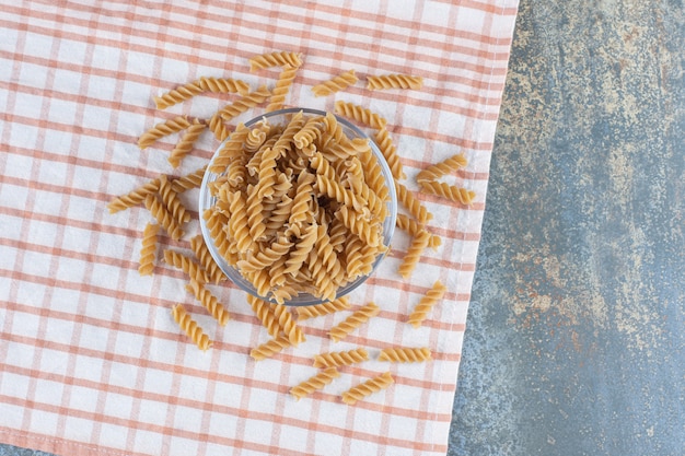 Free photo a glass bowl of fusilli pasta, on the marble background.