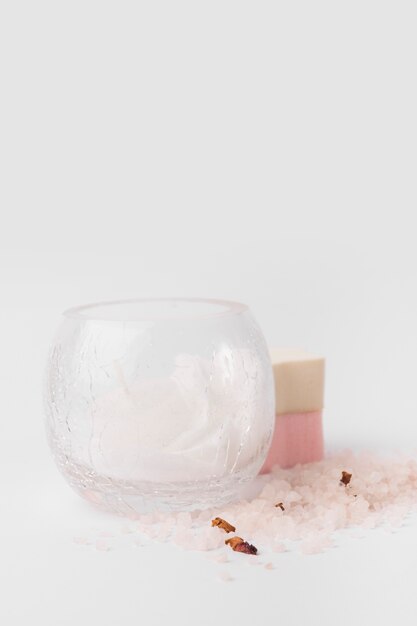 Glass bowl; sponge and herbal salt on white background