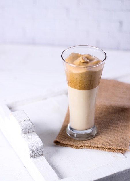 Glass of caramel smoothie on a brown piece of clothing next to a white surface