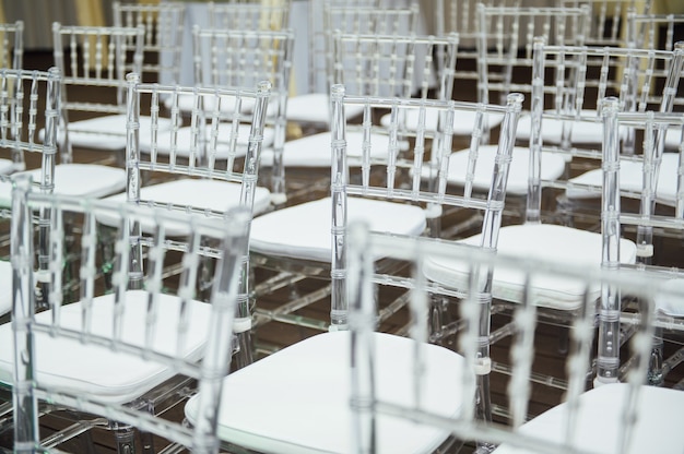 美しい結婚式の外出式でガラスの椅子が一列に並んでいます