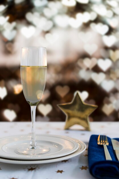Glass of champagne on plate with heart-shaped bokeh effect