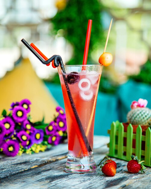 A glass of cherry cocktail with ice and plastic straw pipes