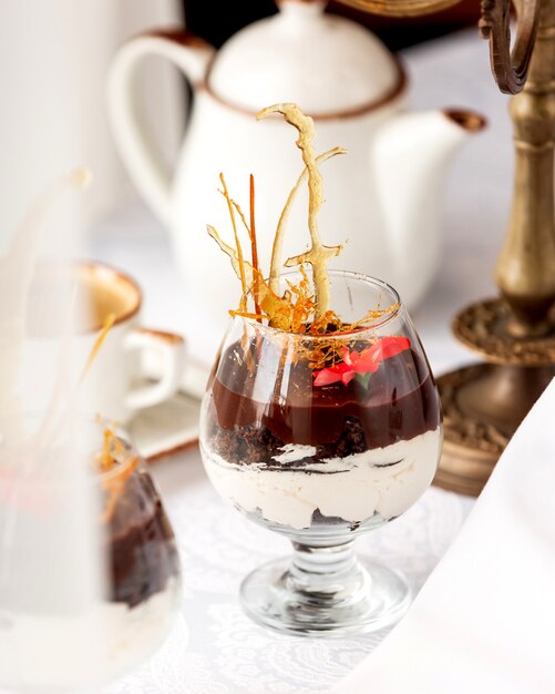 キャラメル装飾と花を添えたバニラクリームとチョコレートデザートのガラス