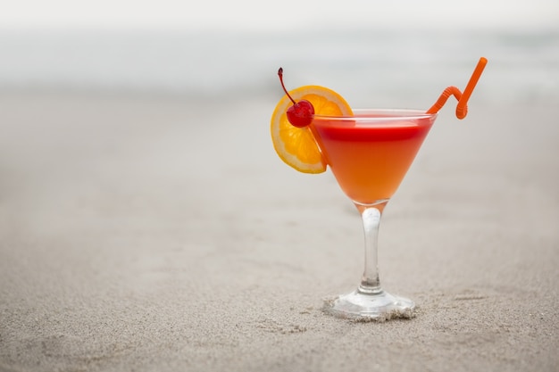 Glass of cocktail drink kept on sand