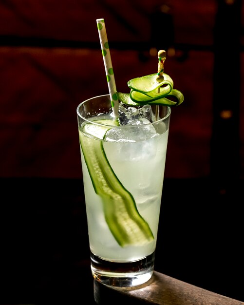 A glass of cocktail with cucumber with ice and paper straw
