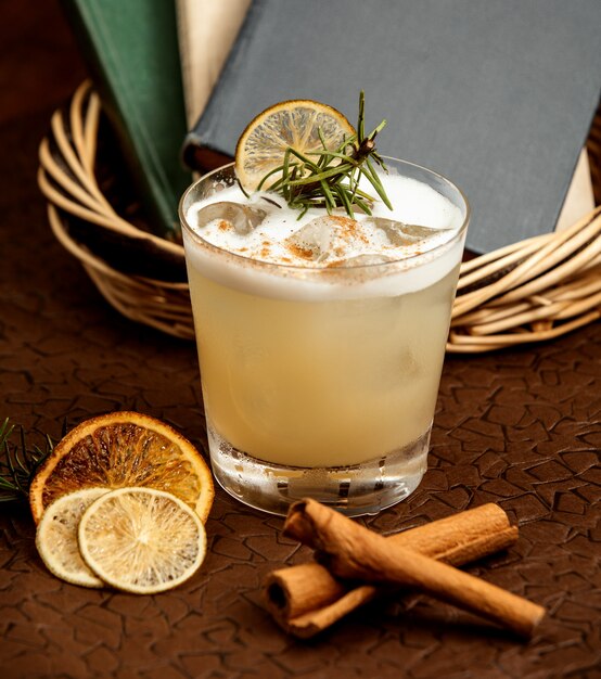 a glass of cocktail with ice garnished with dried lemon and rose marine