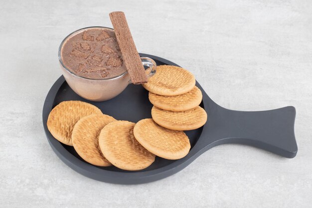 Glass of coffee and various biscuits on dark board