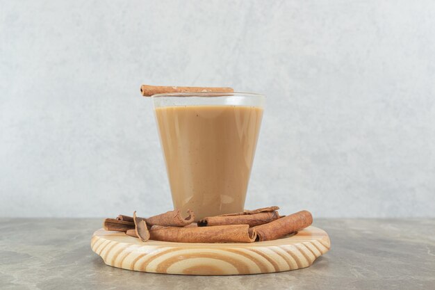 Glass of coffee with cinnamons on wooden board. 