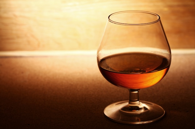 Glass of cognac over wooden surface