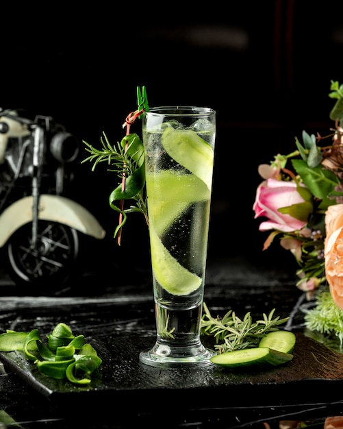 A glass of cold cucumber water garnished with cucumber slice